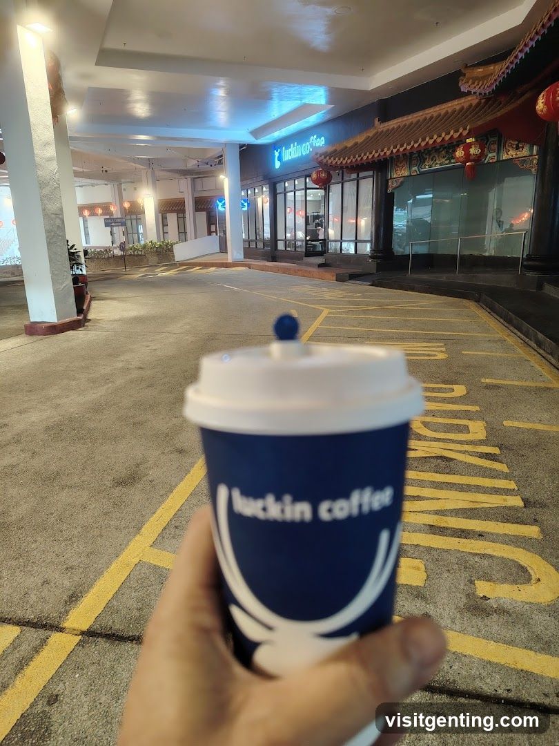 Hand holding Luckin Coffee cup in front of storefront