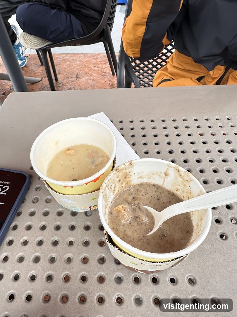 Two paper bowls of soup on a perforated table