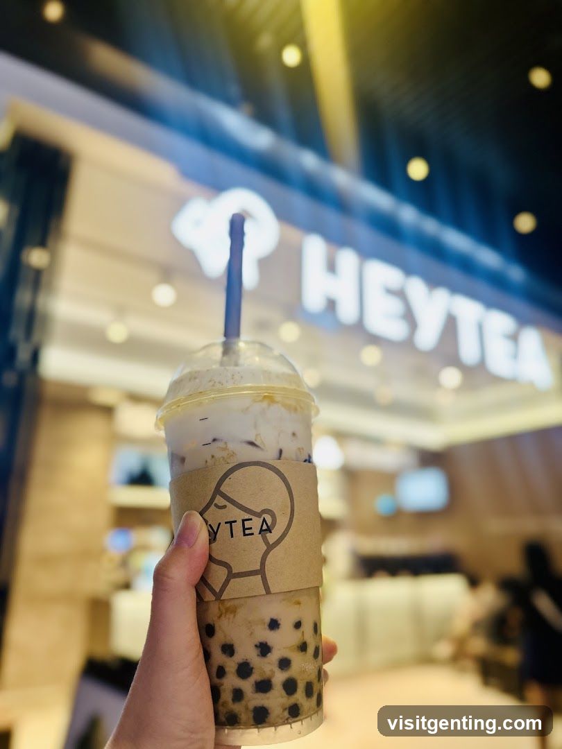 Hand holding a Heytea drink in front of a Heytea storefront