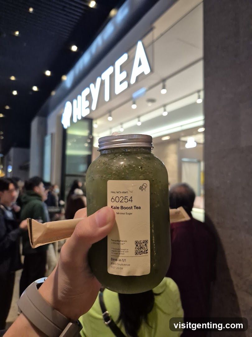 Hand holding a kale boost tea bottle in front of HEYTEA storefront