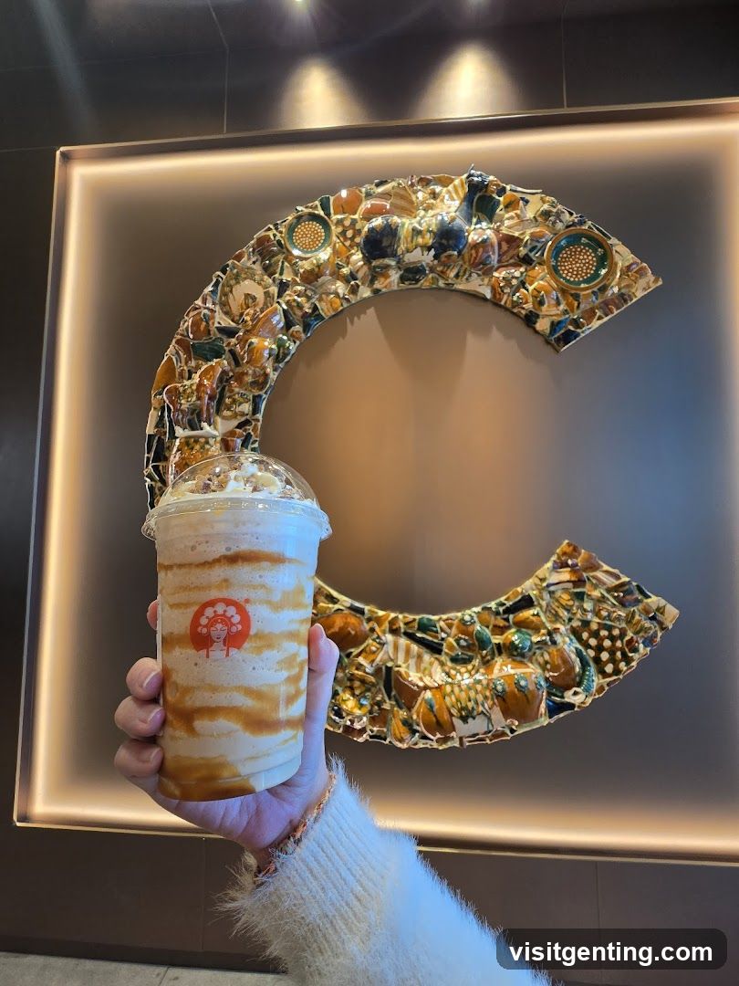 Hand holding drink in front of decorative wall art