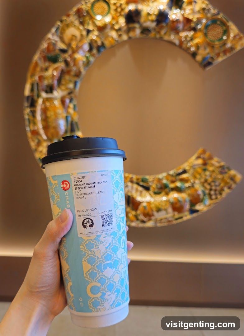 Hand holding ChaGee drink in front of decorative wall art