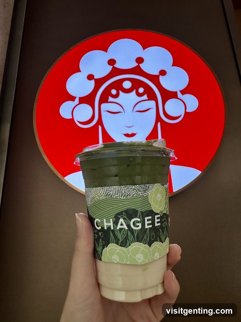 Hand holding a Chagee drink in front of logo
