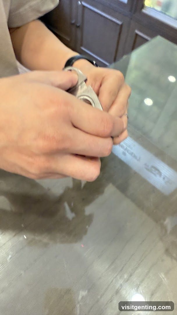 Hands holding a metal object over glass table
