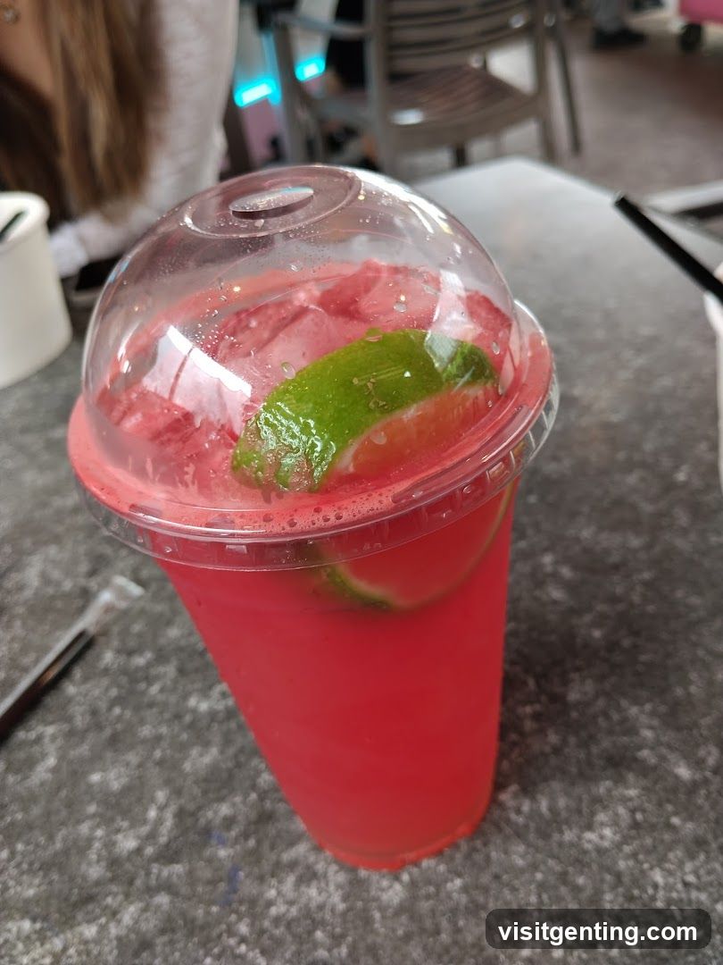 Red beverage with lime slice in plastic cup