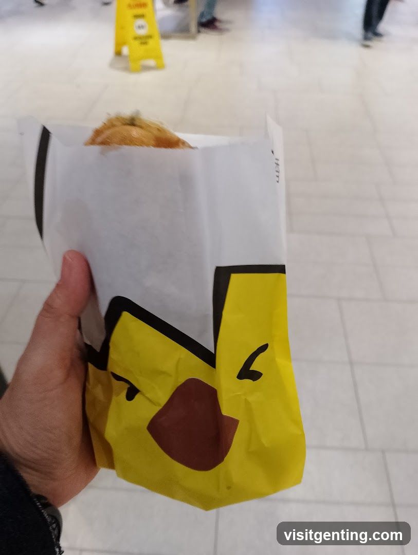 Hand holding food wrapped in branded paper