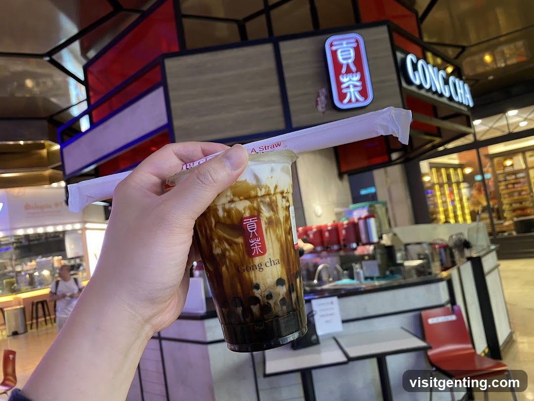 Hand holding Gong Cha drink in a food court