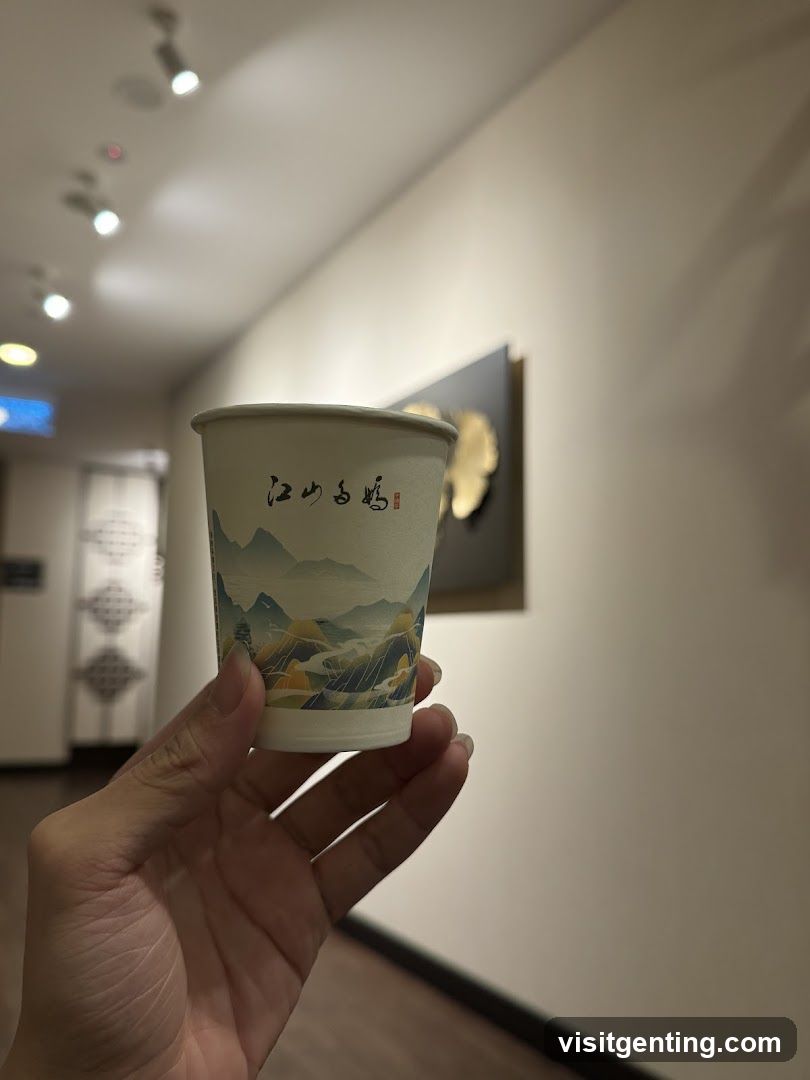 Hand holding a paper cup with Chinese calligraphy and landscape design