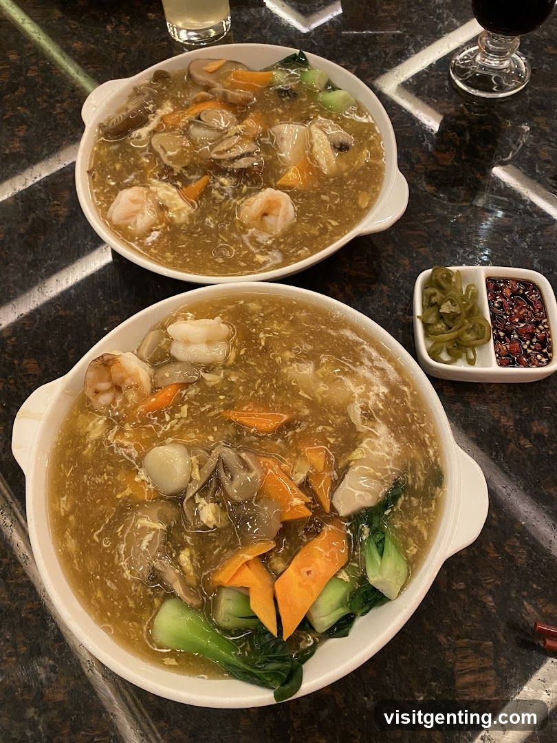 Two bowls of noodle soup with seafood and vegetables