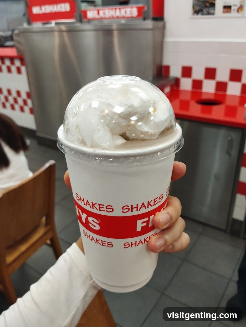 Hand holding milkshake in restaurant interior