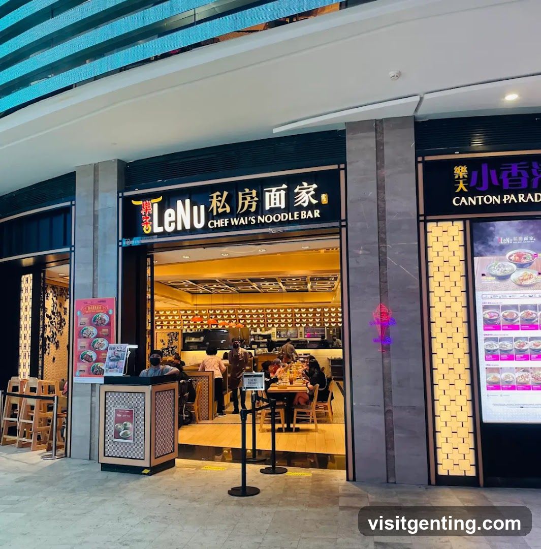 Exterior view of a noodle bar entrance with illuminated signage reading 'LeNu 私房面家 CHEF WAI'S NOODLE BAR'. The facade features modern design elements, including stone pillars and a bright interior visible through the open doorway. Customers are seated inside, staff are present, and there is a small kiosk at the entrance.