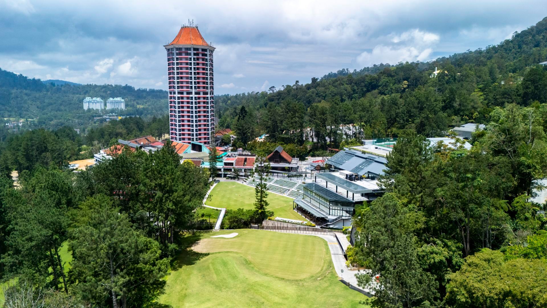 Aerial of Resorts World Awana: the Great Lawn and amphitheatre steps sit between the hotel tower and Awana Village, mid-hill Genting Highlands